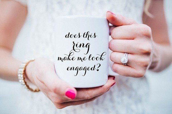A mug with text “Does this ring make me look engaged?”